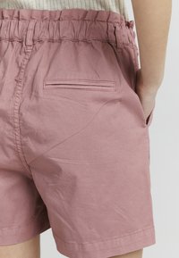 Rosa bomullshorts med elastisk midje, som har en baklomme og en jevn tekstur, som fremhever et avslappet design.