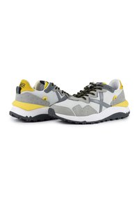 Sneakers grigi e gialli realizzati in rete e suede, con un design testurizzato, lacci neri e una spessa suola bianca con trazione.