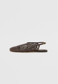 Sandal plana de cuero marrón oscuro con dise�ño de trenzado y correa en el tobillo con un pequeño hebilla dorada, mostrada de lado sobre fondo blanco.