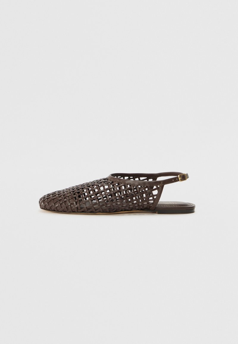 Temno rjave usnjene ravne sandale z tkanim mrežastim dizajnom in paščkom okoli gležnja z majhnim zlatim sponko, prikazane s strani na beli podlagi.
