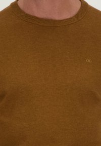 Mosterdgele gebreide trui met een ronde halslijn, voorzien van een subtiele merklogo op de borst, een soepele textuur en geribde boorden.