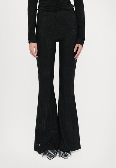 Pantaloni neri a zampa d'elefante realizzati in tessuto testurizzato con una leggera lucentezza. Presentano una vita aderente e accenti metallici appuntiti all'orlo.