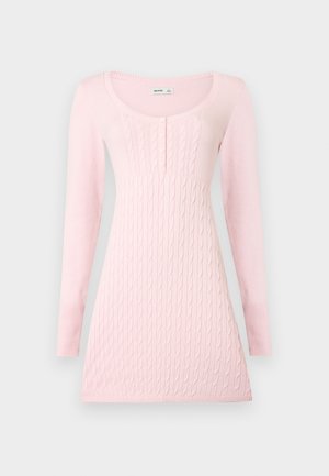 Rochie tricotată roz deschis cu mâneci lungi, modele torsadate, decolteu rotund și patru nasturi mici pe piept.