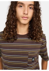 T-shirt rayé marron avec des lignes horizontales bleues et jaunes, col rond, manches courtes et une poche sur la poitrine avec un patch logo.