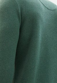 Grüner Pullover mit strukturiertem Strickmuster, featuring einem Rundhalsausschnitt und einer figurbetonten Silhouette. Weiches Material mit dezenten Details.