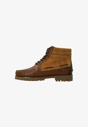 Bruine leren en tan suede enkelboot met veters, een moccasin-neus, contrasterende zwarte hak en een robuuste rubberen zool met grip.