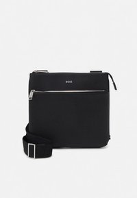 Svart syntetisk axelväska med platt design, justerbar rem, framfack med dragkedja och subtil brandingdetalj.