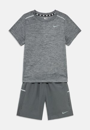 Szürke Nike Dri-FIT rövid ujjú ing hozzáillő sportos rövidnadrággal, mindkettőn fényvisszaverő Nike swoosh logó és légáteresztő oldalsó panelek találhatók.