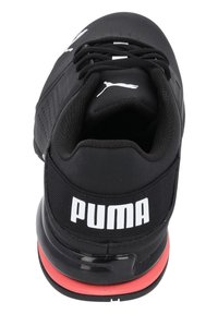 Svart sportskor med en strömlinjeformad design, utrustad med en texturerad ovandel, vadderad krage, framträdande vit Puma-logga och röda sulaaccents.