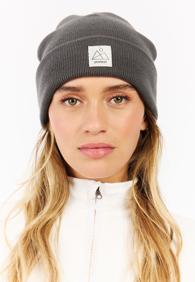 Gray knit beanie featuring a folded cuff and a branded white patch with mountain graphics. Material appears soft with a ribbed texture.
