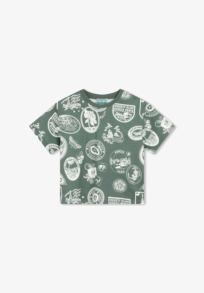 T-shirt en coton vert avec un col rond, ornée d'impressions graphiques blanches représentant divers timbres et motifs sur le tissu. Manches courtes.