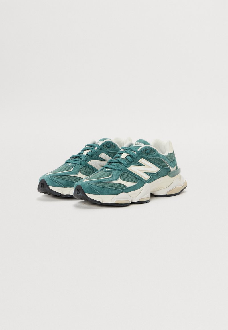 Türkis-weiße Sneakers mit einem Obermaterial aus Mesh und Wildleder, akzentuiert mit einem großen weißen Logo, strukturierten Sohlen und einer voluminösen Silhouette.