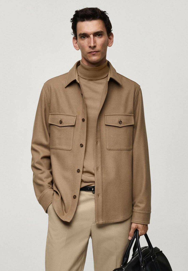 Bruine wollen blend overhemdjack met twee klepzakken, knoopsluiting en een zachte textuur, gedragen over een bijpassende coltrui en beige broek.