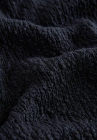 Donker marineblauwe gebreide stof met een textuurpatroon, met verschillende steekstijlen en een zachte, donzige oppervlakte.