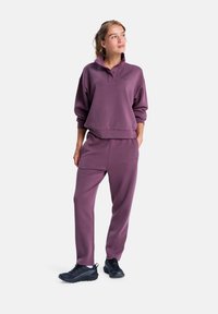 Lila sweatshirt och matchande byxor med en avslappnad passform, i bomullsmaterial, hög krage och sidfickor; kombinerat med svarta träningsskor.