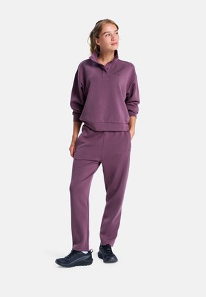 Sweatshirt violet et pantalon assorti avec une coupe décontractée, en matériau coton, col montant et poches latérales; associé à des chaussures de sport noires.