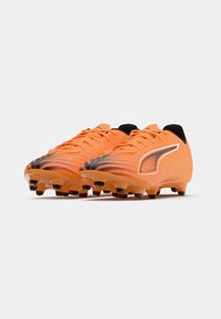 Scarpe da calcio arancioni con tomaia testurizzata, accenti neri e lacci neri. Presentano un design a motivo e tacchetti sagomati per una migliore trazione.