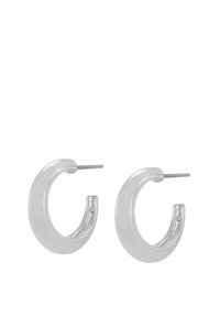 Une paire de boucles d'oreilles en argent lisse et épais en forme de créole avec fermoir à tige, présentées sur un fond blanc.