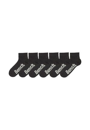 Sechs Paare schwarze Knöchelsocken mit weißem "Bench."-Logo an der Seite, nebeneinander auf weißem Hintergrund angeordnet.