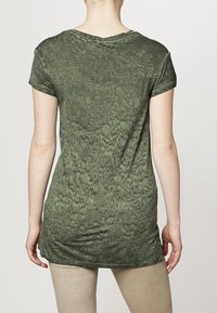 Camiseta verde de manga corta con un patrón texturizado, diseño ligeramente alargado y cuello redondo, confeccionada en una tela suave.