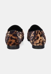 Par de zapatos planos con un patrón de leopardo marrón y negro, con forro interior negro y tacones bajos negros, mostrados desde atrás.