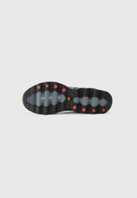 Schwarze Sneaker-Sohle mit roten Akzenten, strukturiertes Gummi für besseren Halt und eine sichtbare Luftpolsterungseinheit. Besitzt ein Muster aus Rillen und Erhebungen.
