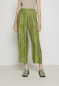 Zielone plisowane spodnie o szerokich nogawkach z elastycznym paskiem w talii, połączone z jasnoszmaragdowymi klapkami na obcasie blokowym z kontrastującym przeszyciem.