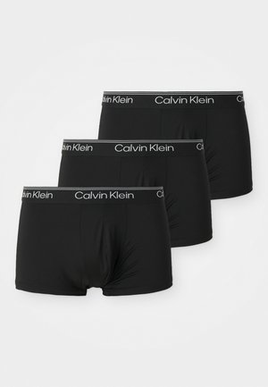 Schwarze Boxershorts aus dehnbarem Material, mit einem weißen Calvin Klein Logo-Bund und einer glatten Oberfläche ohne sichtbare Muster.