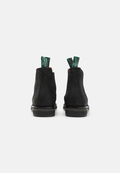 Botas de tobillo de ante negro con una textura suave, que presentan tiradores verdes y un tacón bajo y resistente. Diseño simple con detalles de costura sutiles.