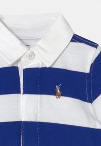 Vit och blå randig polo skjorta med vit krage och en liten broderad polo spelare logotyp på bröstet.