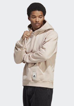 Beige Kapuzenpullover aus weichem Stoff, mit großer Kapuze, Vorderseite-Tasche, geripptem Saum und einem Adidas-Logo in der Nähe des unteren Endes.