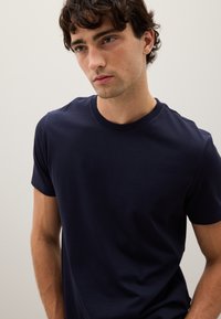 T-shirt girocollo blu navy in tessuto di cotone, maniche corte, design aderente, texture liscia, dettagli minimi, adatta per un abbigliamento casual.