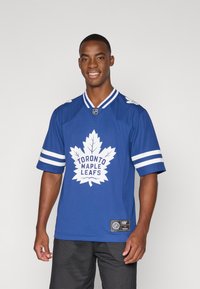Blå Toronto Maple Leafs-drakt med hvite detaljer, som har et stort bladmønster og striper på ermene. Laget av pustende stoff. Korte ermer.