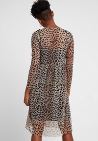 Leopardenmuster-Kleid aus transparenter Stoff, mit langen Ärmeln und gerafftem Taillenbereich für eine fließende Silhouette. Hellbraune und schwarze Töne.