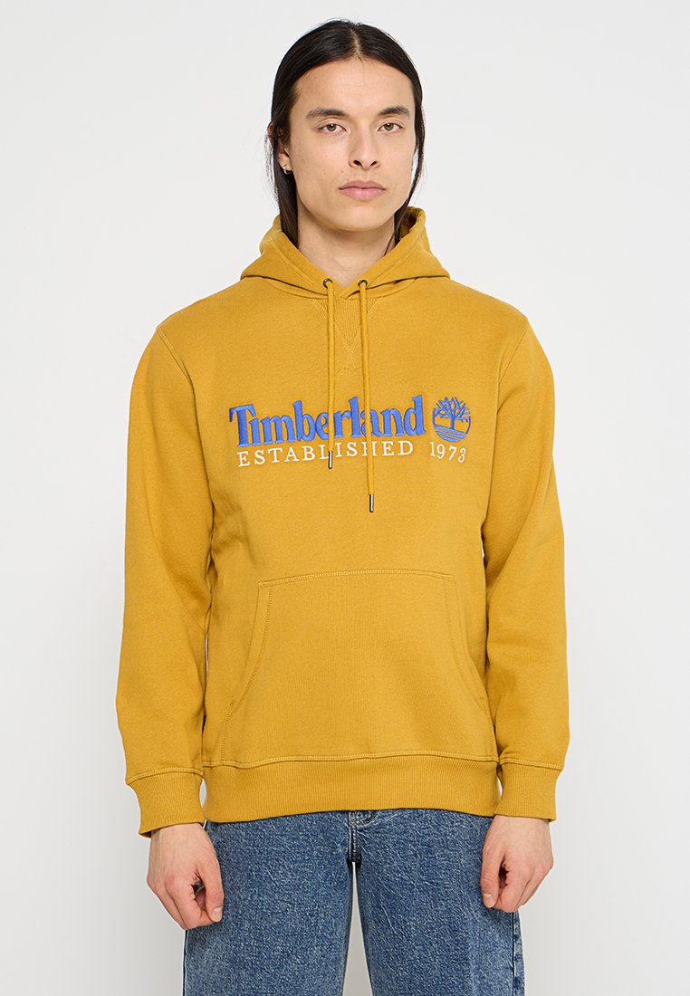 Felpa gialla realizzata in tessuto morbido, con tasca frontale, cappuccio con cordino e logo stampato blu. Vestibilità casual e polsini a coste.