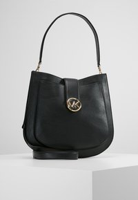 Czarna skórzana torebka o zaokrąglonym kształcie, z magnetycznym zapięciem i złotym logo. Posiada krótki pasek na ramię i gładką fakturę.