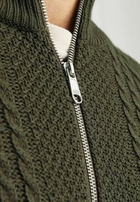Olivgrüner, gestrickter Reißverschluss-Cardigan mit einem strukturierten Zopfmuster, silbernem Metall-Reißverschluss und hohem Kragen.
