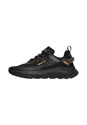 Baskets noires W6YZ avec semelle épaisse tachetée, accents marron, lacets à l'avant et languette sur le talon, vues de côté.