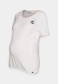 T-shirt de maternidade branca com acabamento em rosa claro, mangas curtas, decote redondo e um design gráfico de ondas no peito. Barra ajustável.