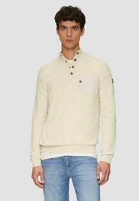 Off-white gebreide pullover met een hoge kraag, knoopsluiting en een borstzak. Heeft ribgebreide manchetten en zoom, met subtiele stikdetails.