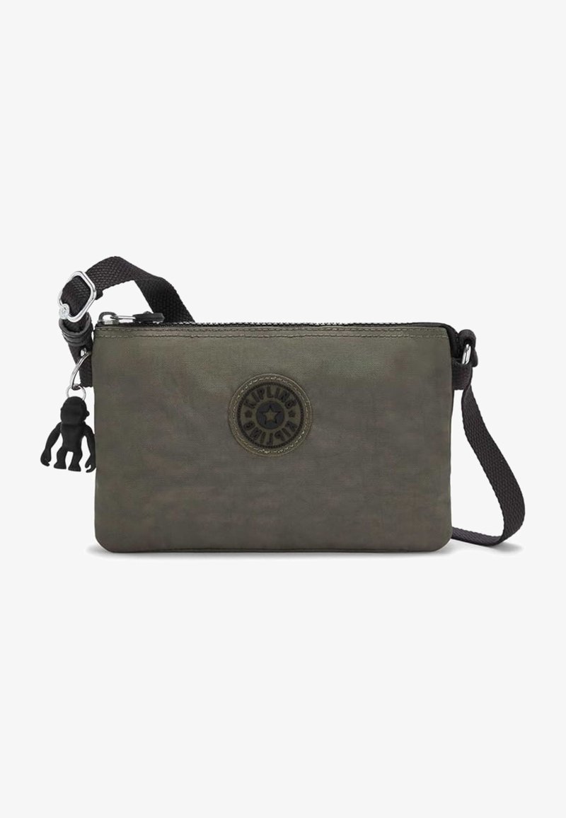 Kleine olivgrüne Umhängetasche mit verstellbarem schwarzem Riemen, rundem Logo-Patch, Reißverschlussverschluss und schwarzem Affen-Schlüsselanhänger.