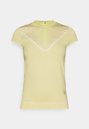 Short-sleeve, light yellow sport shirt with a high collar, a front zipper in neon green, and subtle geometric patterns on the fabric.