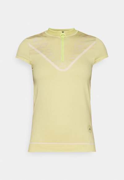 Chemise de sport à manches courtes, de couleur jaune clair, avec un col haut, une fermeture éclair avant en néon vert et de subtils motifs géométriques sur le tissu.