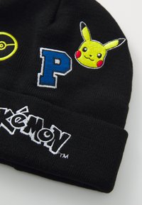 Svart strikket lue med broderte motiver: en gul Poké Ball, blå "P" og Pikachus ansikt. "Pokémon"-logoen brodert i hvitt.
