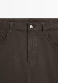 Mørkebrune denimbukser med standard taljebånd, lukning med metalknap og traditionelt design med 5 lommer. Glat tekstur.