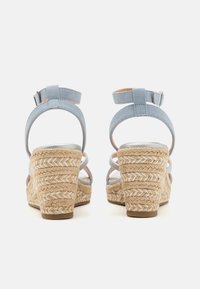 Sandales à talons compensés en suède bleu avec un talon en paille tressée et une bride à la cheville. Présente un doublure intérieure lisse et des brides larges en similicuir.
