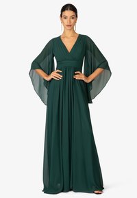 Abito lungo verde realizzato in tessuto fluido con scollatura a V profonda e maniche a mantella. Presenta dettagli arricciati in vita.