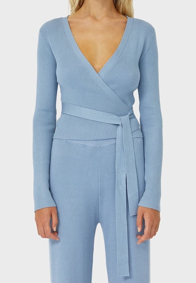Hellblaues geripptes Strick-Wickeltop mit langen Ärmeln und tiefem V-Ausschnitt; verfügt über einen passenden Stoffgürtel, der in der Taille gebunden ist.