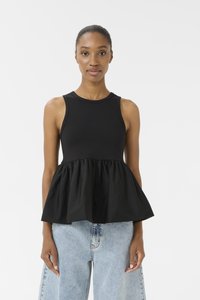 Top nero senza maniche con busto aderente e orlo a peplo svasato, realizzato in morbido tessuto di cotone. Indossato con jeans a palazzo in denim blu chiaro.