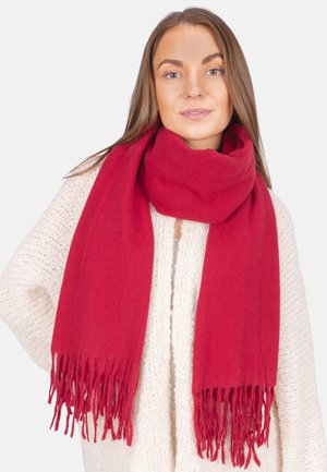 Écharpe rouge avec des extrémités à franges, faite d'un matériau doux, portée lâchement autour du cou par-dessus un pull crème texturé.